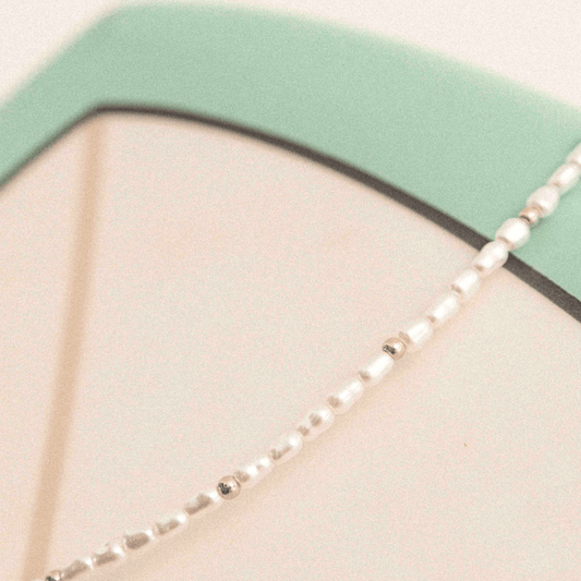 Detailaufnahme der Kette mit Imitationsperlen und goldfarbenem Glanz