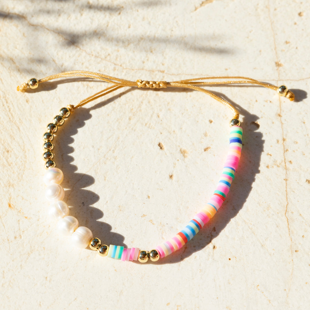 Armband mit bunten Lehmperlen, echten Süßwasserperlen und goldfarbenen Details auf beigefarbenem Zugband – Pearl Vibes von Wild Tides ohne farbretusche