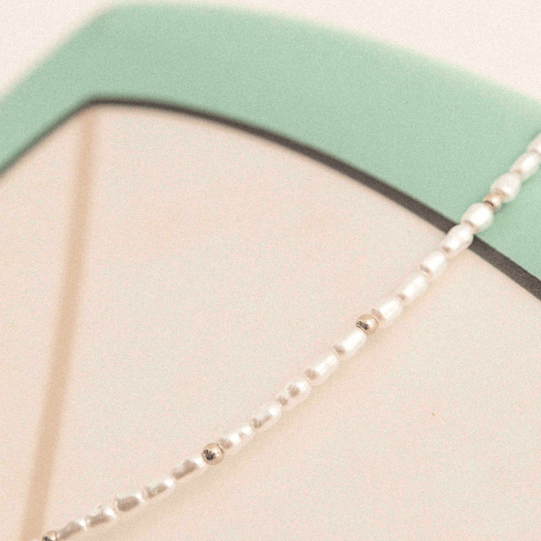 Detailaufnahme der Kette mit Imitationsperlen und goldfarbenem Glanz
