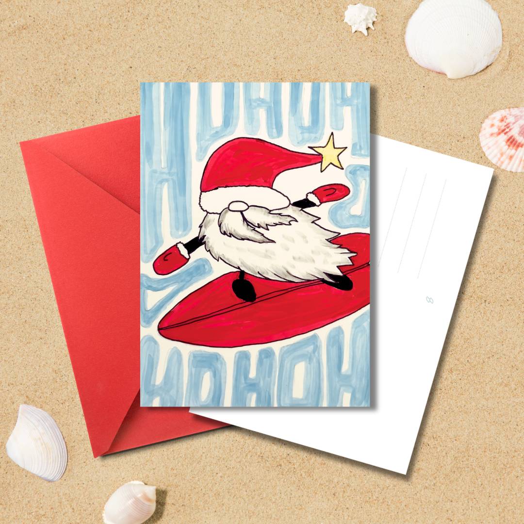 Handgezeichnete Weihnachtskarte „Ho Ho Surf“ mit surfendem Weihnachtsmann und rotem Umschlag auf Sandhintergrund