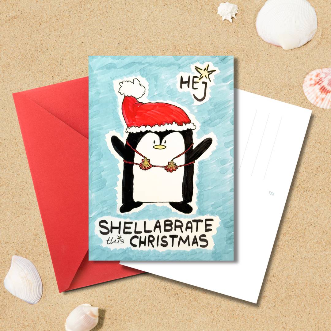 Handgezeichnete Weihnachtskarte „Shellabrate this Christmas“ mit Pinguin und rotem Umschlag auf Sandhintergrund