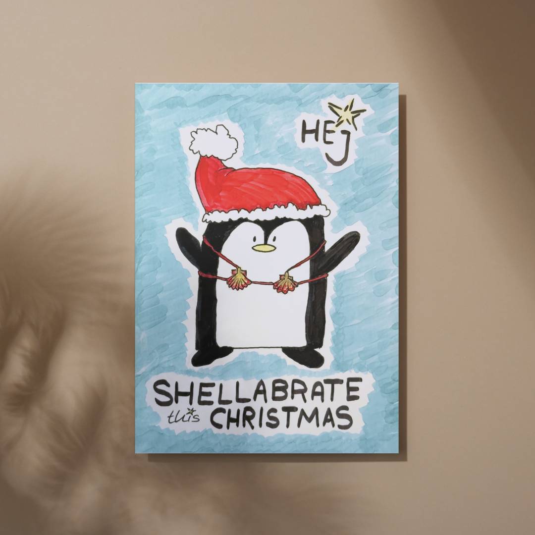 Karten Vorderseite: Illustration eines Pinguins mit Weihnachtsmütze und Muschelkette, Schriftzug „Shellabrate this Christmas“